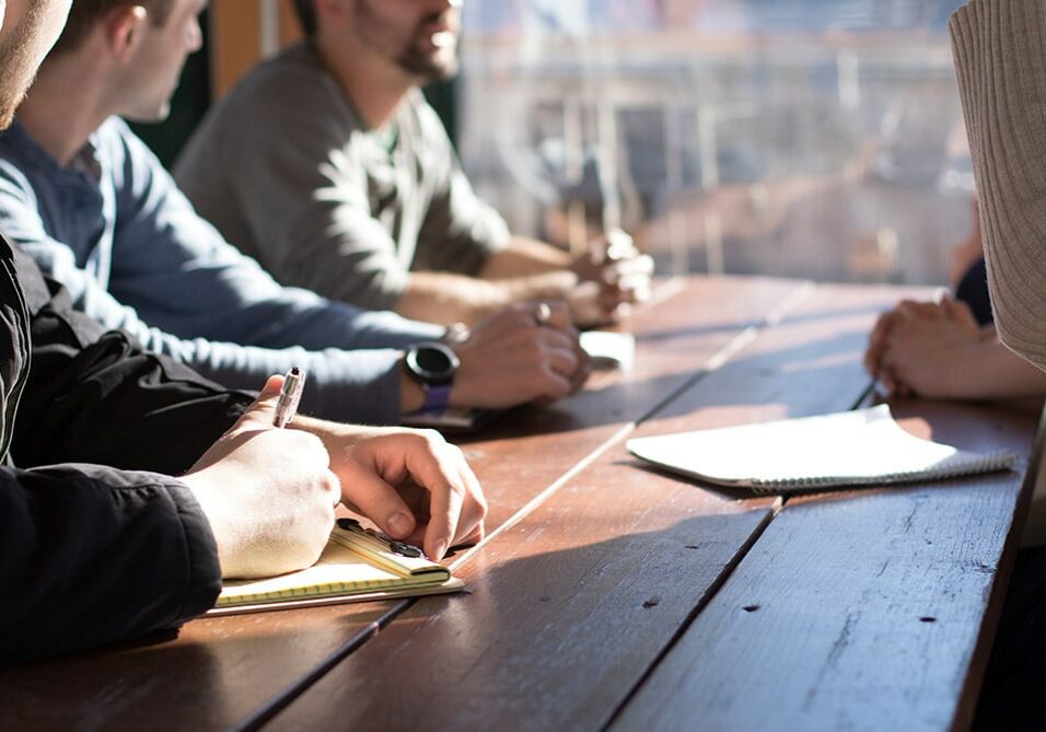 A group of people in a committees, discussing at a table.